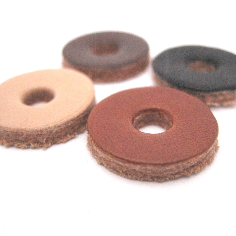 Close-up of 4 round leather washers in 4 different colors on a white background