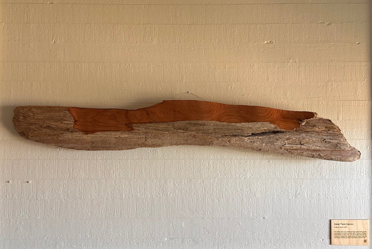 Driftwood log art piece mounted on a white wall above a fireplace in a coastal hotel