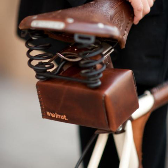 A small folded leather box pannier bag mounted on the back of a Brooke bicycle saddle