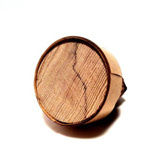 A small wood plug wrapped with a length of adhesive-back double-sided tape on a white background