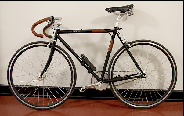 A black road bicycle with brown leather handlebar wraps and portage carrier strap