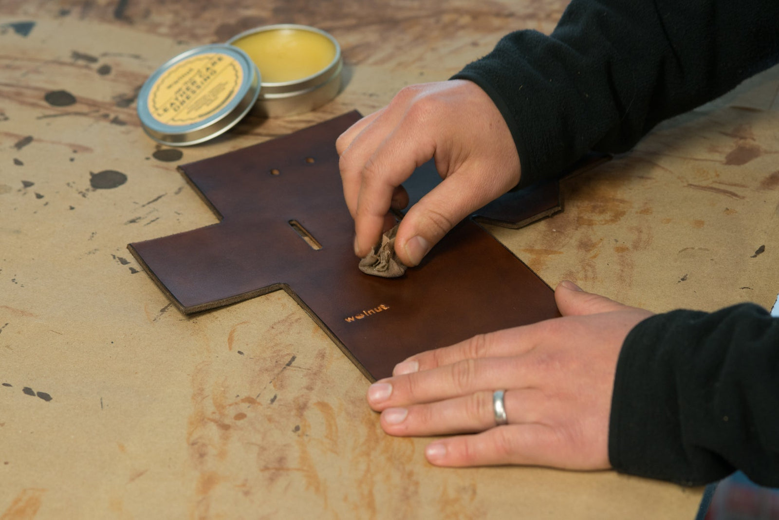 Hands applying a leather conditioner to a piece of veg-tan leather