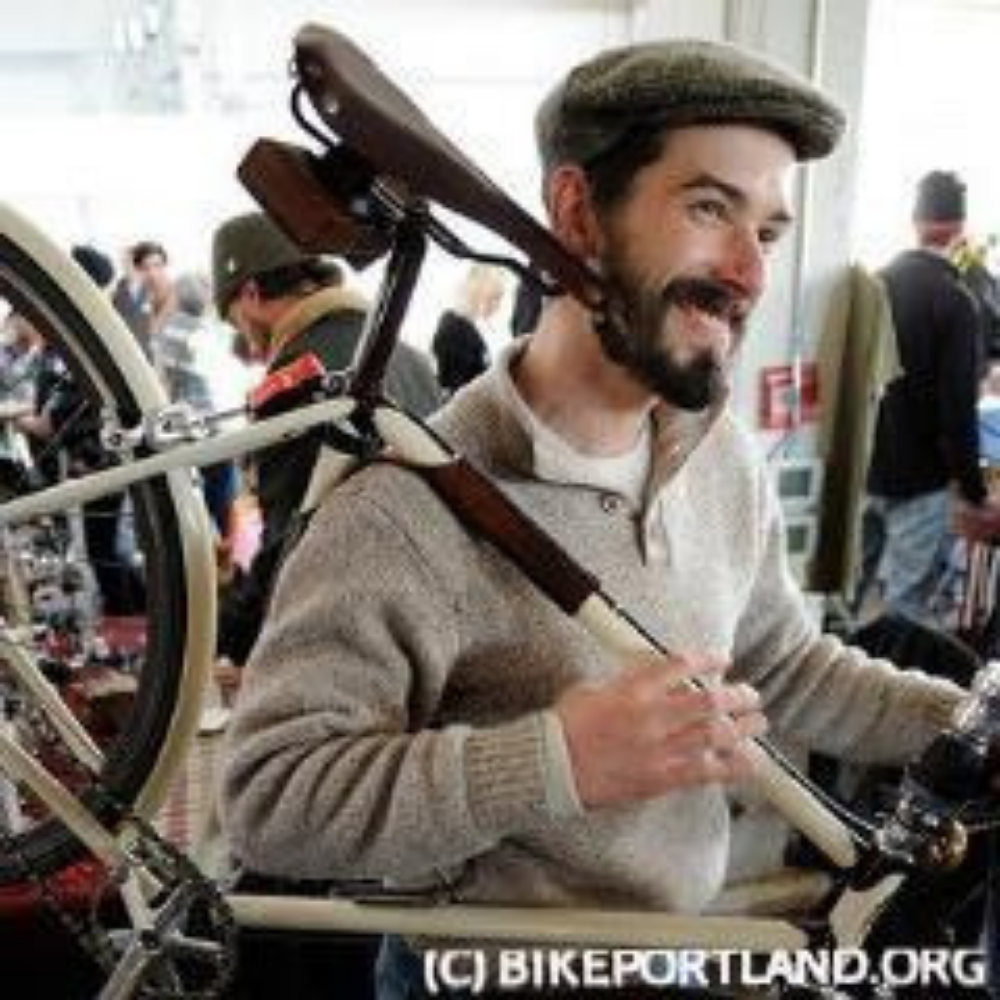 A dapper man in wool tweed hoisting a bicycle onto his shoulder with a cushioned leather strap