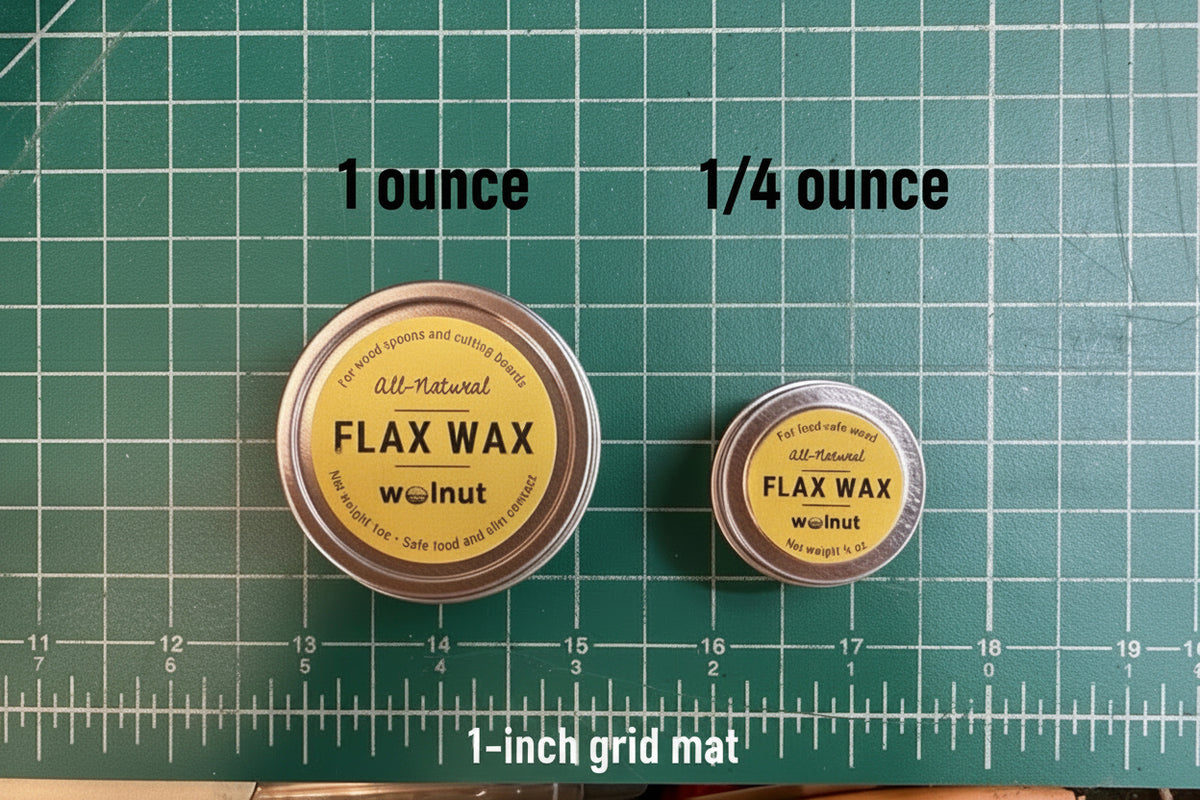 Two small round metal tins of Flax Wax, placed on a green cutting mat with grid lines and measurement markings with text denoting the larger tin is 1-ounce and the smaller is 1/4 ounce.
