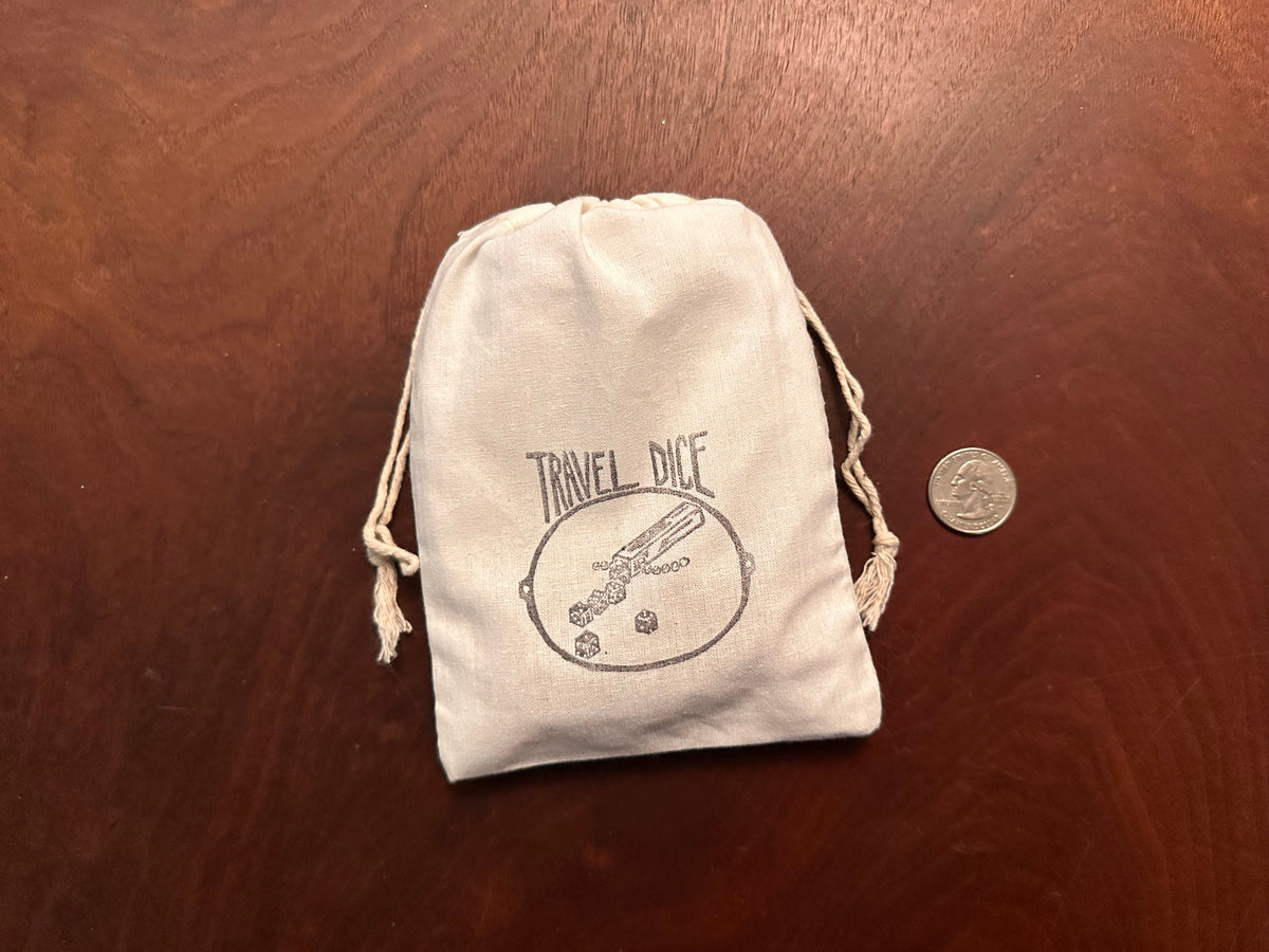 The Travel Yacht kit shown how it arrives and how it travels, with the parts inside the 5" x 7" bag, tied with a double-drawstring, and a quarter next to it for scale. 