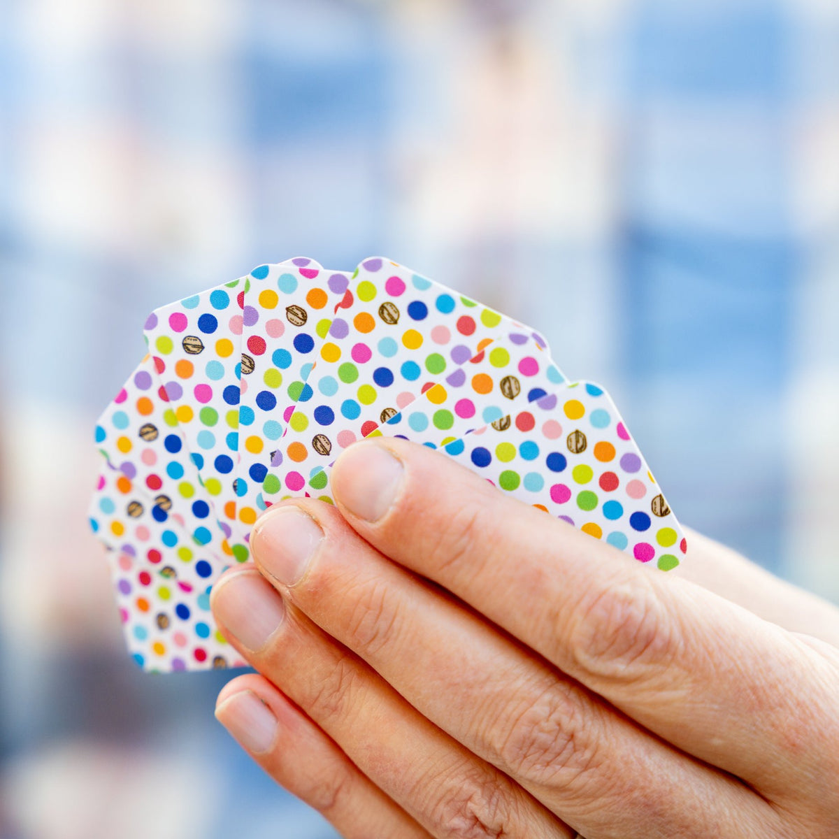 Close-up of a person's hand holding a fanned set of small micro sized domino playing cards