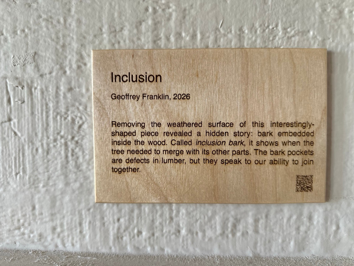 Wood artist placard (plaque) on a textured white wall with artwork name, artist name, year, artist statement, and QR code 