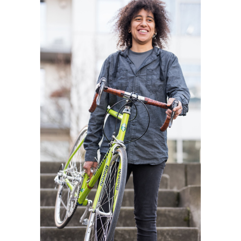 Person carrying green bike downstairs using the "little lifter" leather bike handle