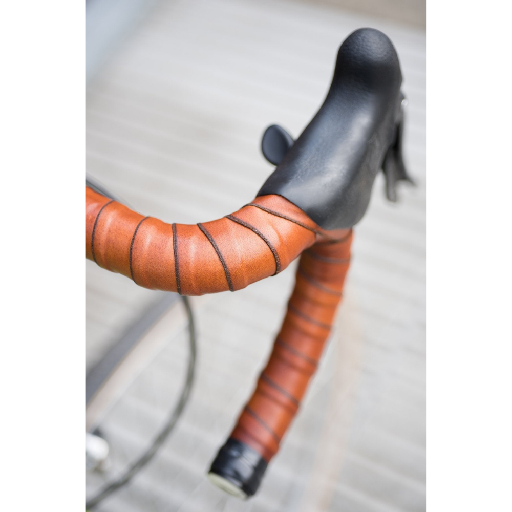 Bird's eye view looking down on bicycle drop bars with honey leather coiled around handlebars