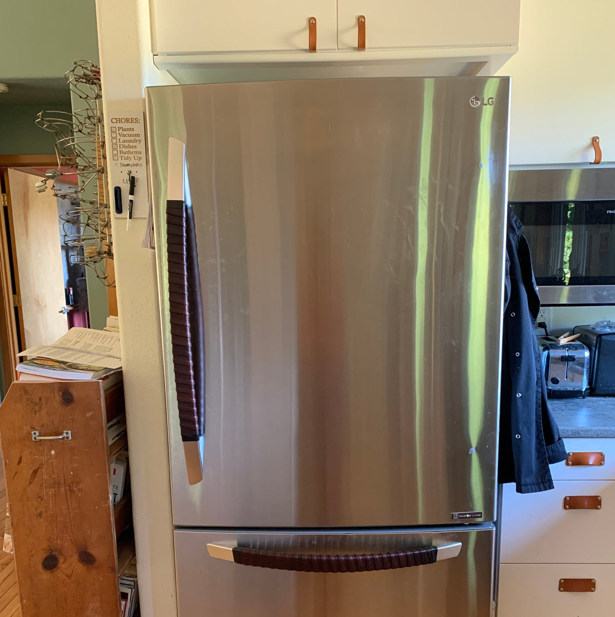 Customer photo of a kitchen refrigerator with two Oswego leather wrap kits, one on each handle. The fridge is stainless steel and the Oswego handle is dark brown. 