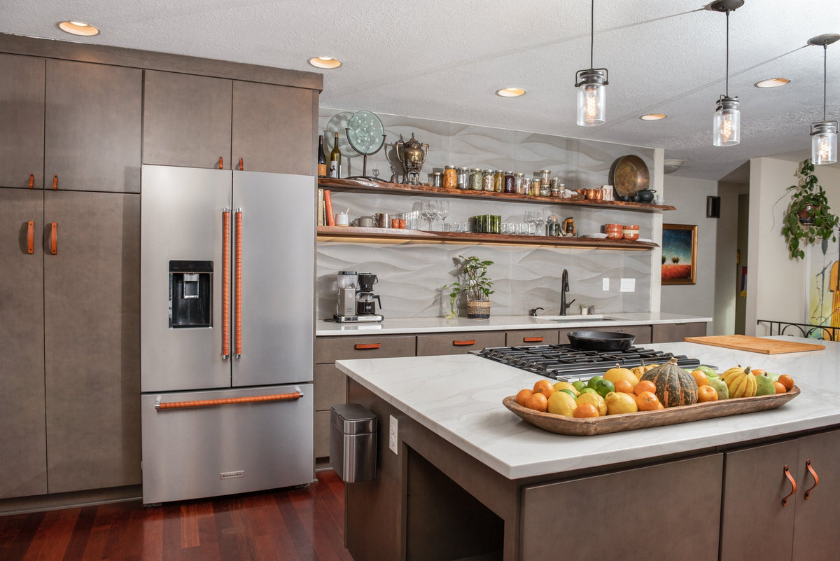 Stepped-back photo of a beautiful gray and olive green kitchen remodel with honey leather appliance handle wraps and honey door, drawer, and cabinet pulls and handles. 