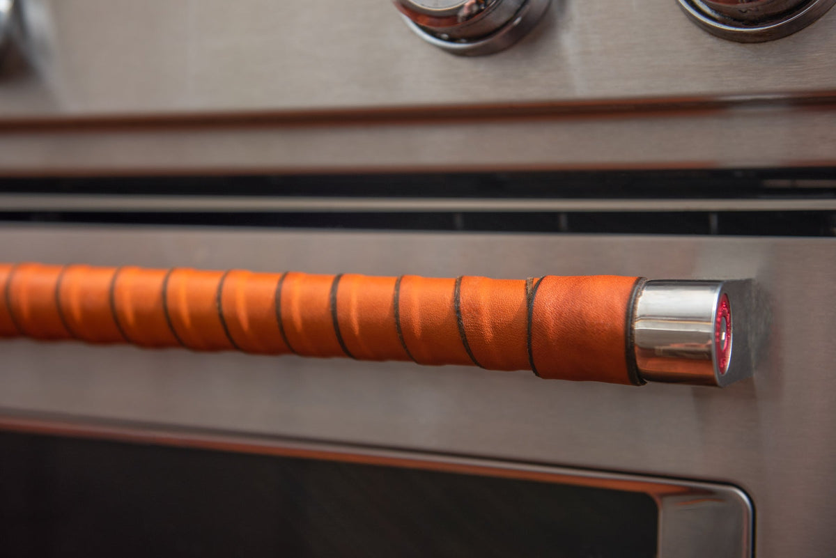 Very close-up detail shot of the end of a leather-wrapped oven handle.