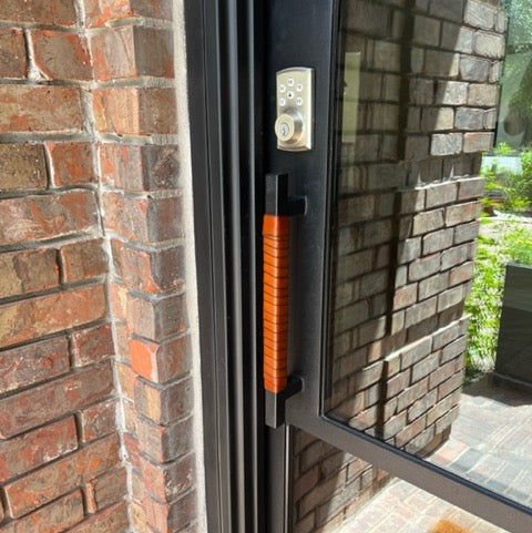 Customer photo of an installed Oswego leather wrap on a small square outdoor metal door handle. The leather is honey on a black matte metal door and handle. 