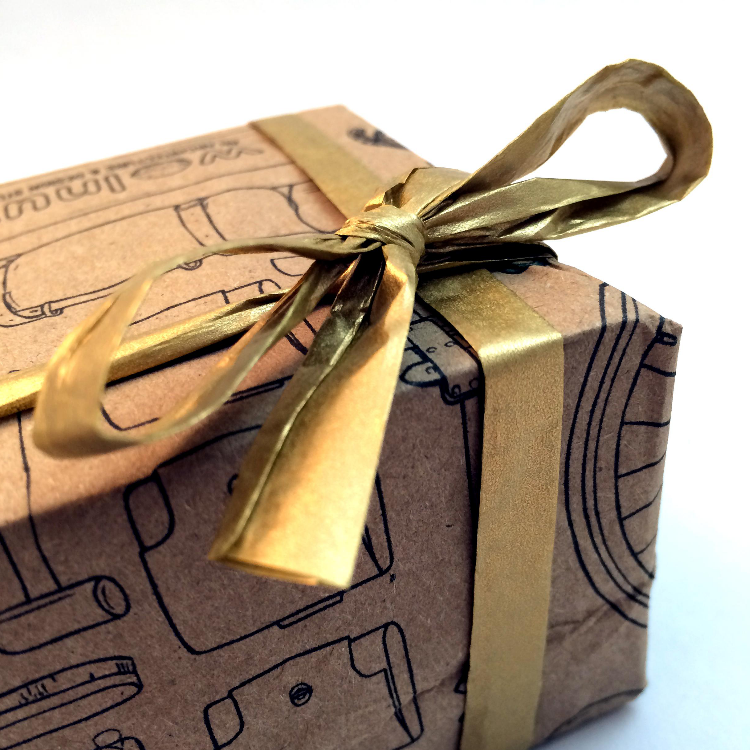 Close-up of a gift wrapped in Walnut's kraft recycleable wrapping paper with a gold paper raffia ribbon